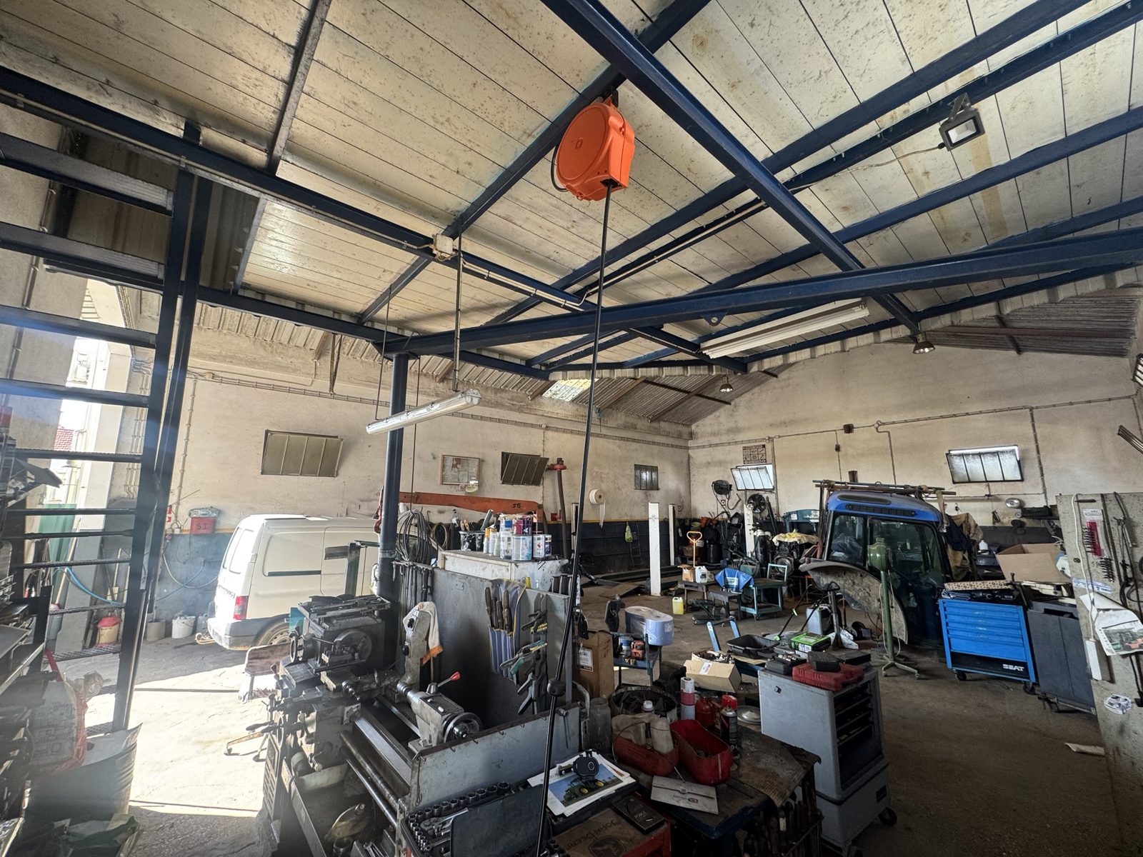 Interior da oficina, com um trator em reparação